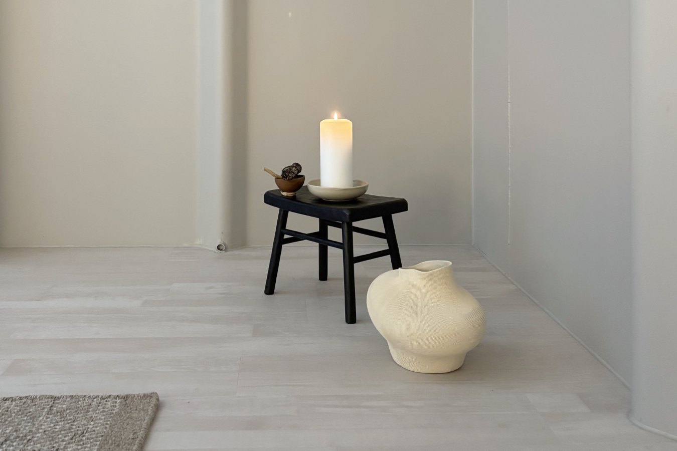 Interior Design mit Hocker, Vase, und Kerze vor grauer Wand